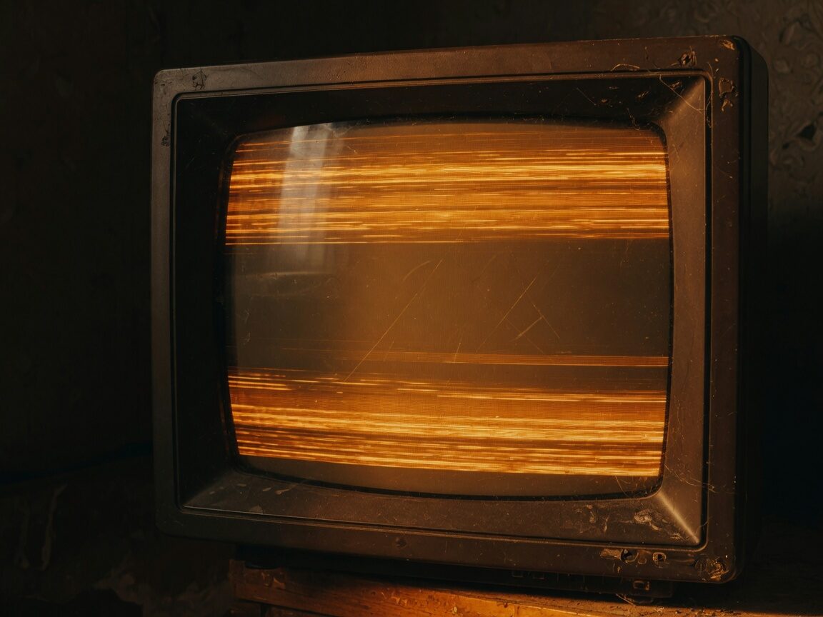 Close-up of a dusty CRT filled with amber scanlines, no readable text.